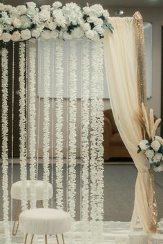 an elegant wedding setup with white flowers and sheer draping on the wall,