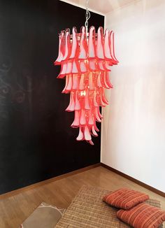 a pink chandelier hanging from the ceiling in a room with wood flooring