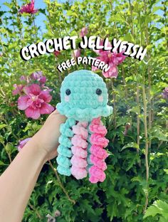 a crocheted jellyfish with pink and blue flowers in the background