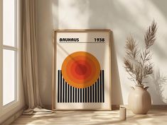 an orange and black poster sitting on top of a wooden table next to a vase