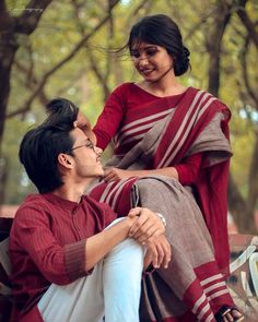 a man sitting on top of a bench next to a woman in a red dress