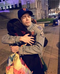 a man and woman hugging each other on the sidewalk