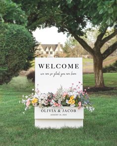 a welcome sign in the grass with flowers