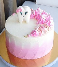 a pink and white cake with a tooth on top