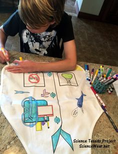 a young boy sitting at a table drawing on a piece of paper