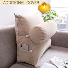 a beige pillow sitting on top of a couch next to a lamp