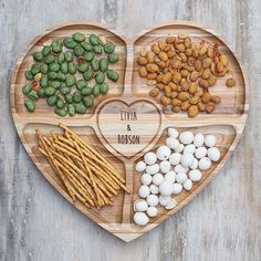 a wooden heart shaped plate filled with nuts and other food items on top of it