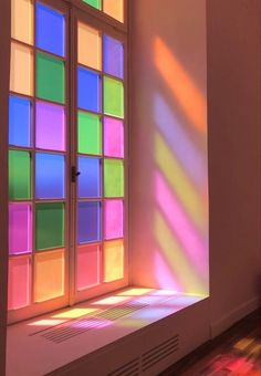 an open window with multicolored glass blocks on the wall and floor in front of it