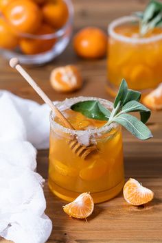 a close up of a drink on a table with oranges and leaves in the background