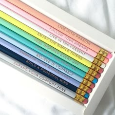 six colored pencils in a white box with writing on them