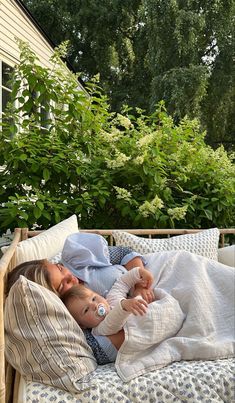 a young child laying on top of a bed next to a baby in a diaper