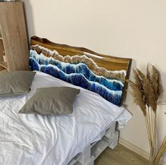 a bed with two pillows on top of it next to a wooden headboard that has waves painted on it