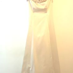 a white dress hanging up against a wall with a flower on the front and bottom