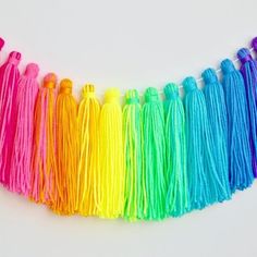 multicolored tassels are lined up on a white surface with one string in the middle