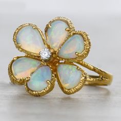 A beautiful and pear shapped opal ring, featuring a romantic side profile of a split shank with a textured finnish. At it's center is one bright white diamond measuring to 2.1mm. This authentic antique ring is crafted in 14k yellow gold shaped in as flower. Finger size 5.5. Details: Size: 5.5 14k Yellow Gold 6 Pear Opals Measurement: 6.5x5x2mm Diamonds 1 Round Diamond Measurement: 2.1mm Total carat weight: 0.035cts Prong Set Textured Finish only available at Burdeen's Jewelry. We have many uniqu Elegant Ethiopian Opal Ring For Anniversary, Opal Ring With Rose Cut Diamonds For Anniversary, Elegant Opal Ring With Rose Cut Diamonds, Anniversary Opal Ring With Rose Cut Diamonds, Elegant Ethiopian Opal Ring, Elegant Pear-shaped Opal Ring, Teardrop Diamond Opal Ring For Anniversary, Elegant Yellow Gold Pear-shaped Opal Ring, Fine Jewelry Opal Rings In Pear Shape