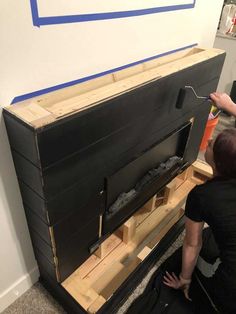 two people are working on a large piece of furniture that is being built into the wall