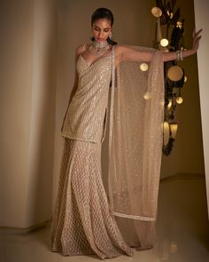 This sharara set features all-over sequin embroidery on a champagne net base. The strappy top is paired with a matching net dupatta.From Seema Gujral's Fiori collection. DELIVERY TIMEPlease allow 8-12 weeks for your outfit to arrive. FABRIC DETAILSNet Professional cleaning only. Champagne Indian Outfit, Sequin Sharara, Indian Fits, Seema Gujral, Sharara Designs, Net Lehenga, Indian Dresses Traditional, Indian Bridal Fashion, Sequin Embroidery