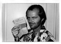 black and white photograph of a man holding up a paper with an article on it