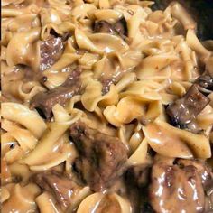 some meatballs and noodles are being cooked in a skillet