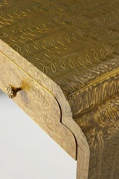 an intricately carved wooden table with gold paint on it's top and bottom