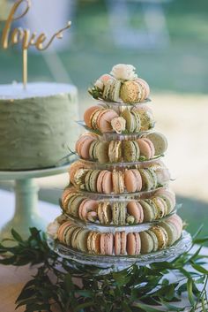 a stack of macaroons sitting on top of a table next to a cake