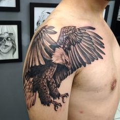 an eagle tattoo on the back of a man's left shoulder and upper arm