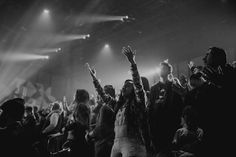 a group of people at a concert with their hands in the air and lights on