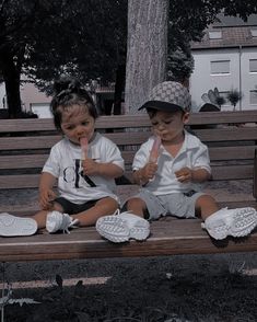 two young children sitting on a wooden bench