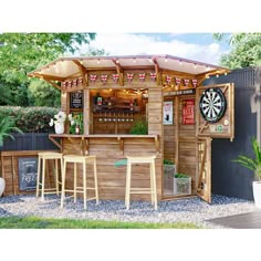 an outdoor bar with darts on the wall and wooden stools in front of it