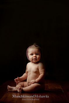 a baby is sitting on the floor and looking at the camera