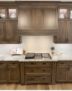 a kitchen with wooden cabinets and white marble counter tops, along with wood flooring