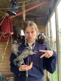 a woman is holding two birds in her hands and pointing at the bird on her finger