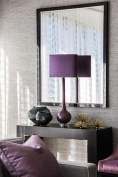 a purple lamp sitting on top of a table next to a mirror and two chairs