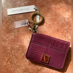 a pink and purple purse with a keychain attached to it on a table