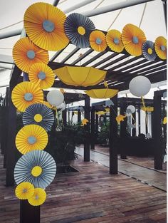 many yellow and white paper umbrellas hanging from the ceiling in an open area with wood flooring