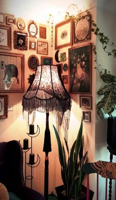 a lamp sitting on top of a table next to a wall filled with framed pictures