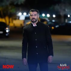 a man standing in the middle of an empty parking lot at night with his hand on his hip