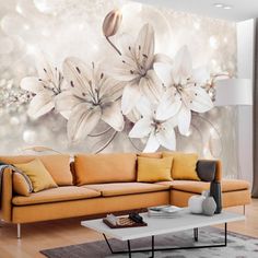 a living room with a couch, coffee table and flower wall mural on the wall