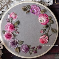 a close up of a embroidery on a piece of cloth with pink and purple flowers