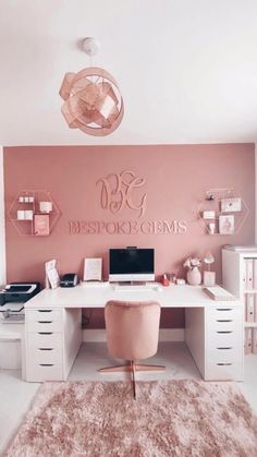 a white desk topped with a laptop computer next to a pink chair and wall art