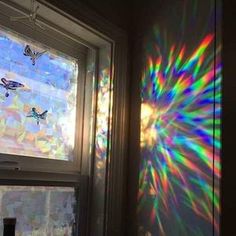 the sun shines brightly through an open window with butterflies on it and in the background, there is a multicolored light pattern