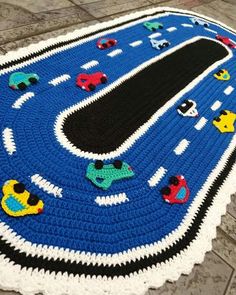 a blue crocheted rug with cars and trucks on it is sitting on the floor