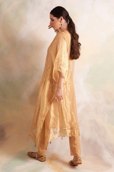 Gold tissue kaftan style kurta with lace trims and tassel hem. Comes with soft modal gold pant.
Component: 2
Pattern: Solid
Neckline: V-Neck
Sleeve Type: Batwing
Fabric: Kurta: Tissue, Pant: Soft Modal
Color: Gold
Other Details: 
Tassel hem
Lace trims
Side slits
Note: Inner worn by the model is not for sale
Occasion: Mehendi and Haldi - Aza Fashions Traditional Kurta With Back Tassel Tie-up For Diwali, Anarkali Kurta With Tassels For Wedding, Anarkali Kurta With Back Tassel Tie-up For Navratri, Anarkali Wedding Kurta With Tassels, Anarkali Kurta For Navratri With Back Tassel Tie-up, Navratri Anarkali Kurta With Back Tassel Tie-up, Festival Straight Kurta With Back Tassel Tie-up, Traditional Drape Kurta With Back Tassel Tie-up For Festivals, Traditional Kurta With Back Tassel Tie-up For Festivals