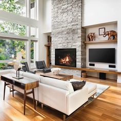 a living room with white furniture and a fire place in the fireplace, surrounded by large windows