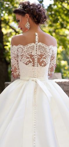 a woman in a white wedding dress with an open back and lace on the top