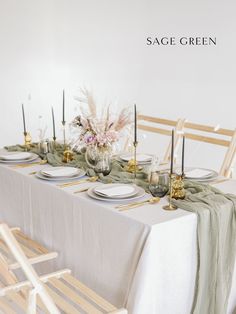 a table set with place settings and flowers in vases on the top, along with candles