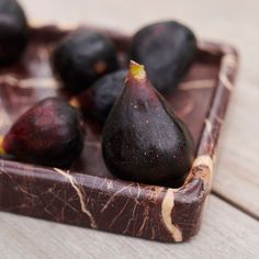 some figs are sitting in a wooden tray on the table and ready to be eaten