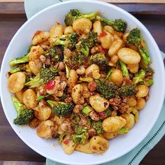 a white bowl filled with broccoli and other food items on top of a wooden table