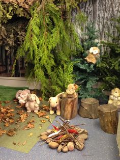 several stuffed animals are sitting on the ground next to some logs and trees in front of them