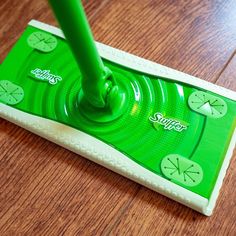 a green mop sitting on top of a wooden floor